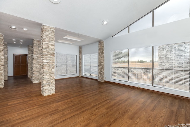 unfurnished living room featuring high vaulted ceiling, ornate columns, and dark hardwood / wood-style flooring