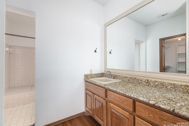 bathroom featuring hardwood / wood-style floors, vanity, and a tile shower