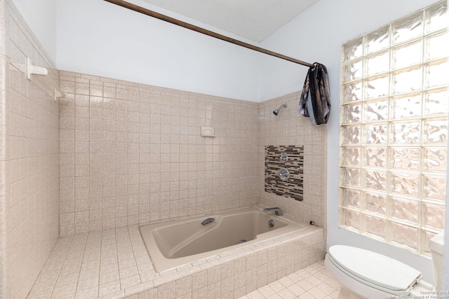 bathroom with toilet, tiled shower / bath combo, and tile patterned flooring