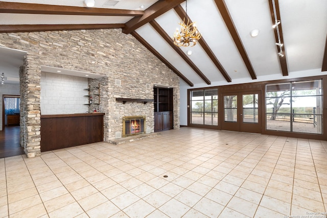 unfurnished living room featuring a stone fireplace, a healthy amount of sunlight, an inviting chandelier, and high vaulted ceiling