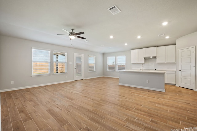 unfurnished living room with light hardwood / wood-style flooring, ceiling fan, and sink