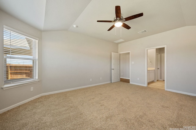 unfurnished bedroom with connected bathroom, light colored carpet, vaulted ceiling, and ceiling fan