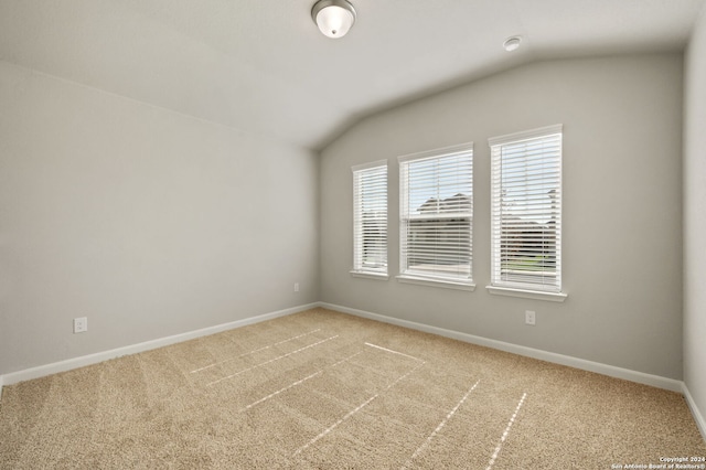 spare room with light colored carpet and lofted ceiling