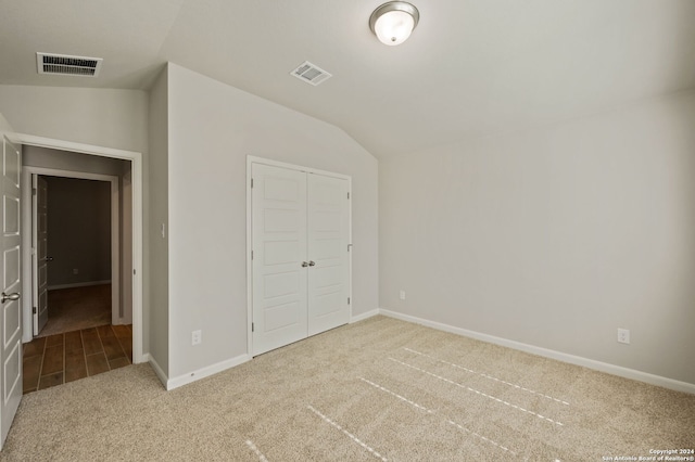 unfurnished bedroom with vaulted ceiling, light carpet, and a closet