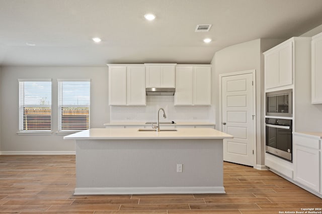 kitchen featuring white cabinetry, a kitchen island with sink, and stainless steel oven