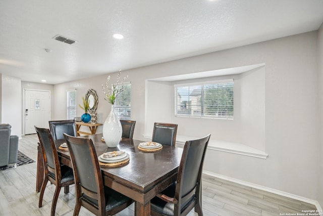 dining space featuring light hardwood / wood-style floors, a chandelier, and a textured ceiling