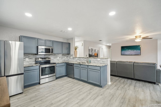 kitchen featuring light hardwood / wood-style floors, kitchen peninsula, tasteful backsplash, ceiling fan, and appliances with stainless steel finishes