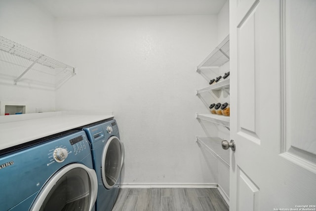 laundry room with washing machine and clothes dryer and light hardwood / wood-style flooring