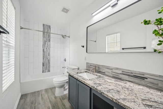 full bathroom featuring hardwood / wood-style floors, vanity, tiled shower / bath combo, and toilet