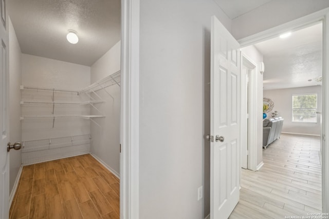 corridor with a textured ceiling and light hardwood / wood-style flooring