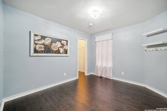 spare room featuring dark wood-type flooring and a textured ceiling