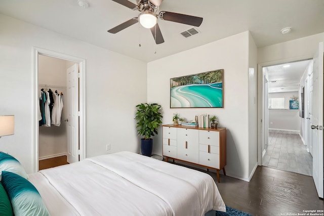 bedroom with a closet, ceiling fan, a spacious closet, and dark hardwood / wood-style floors