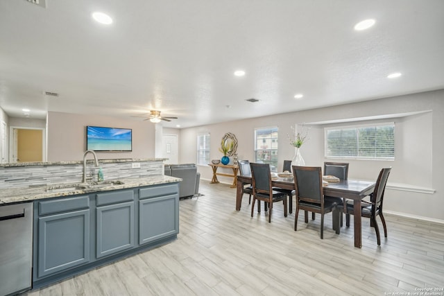 kitchen featuring light stone counters, dishwasher, sink, ceiling fan, and light hardwood / wood-style flooring