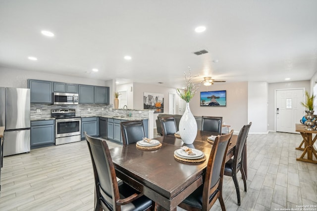 dining space with light hardwood / wood-style floors, ceiling fan, and sink