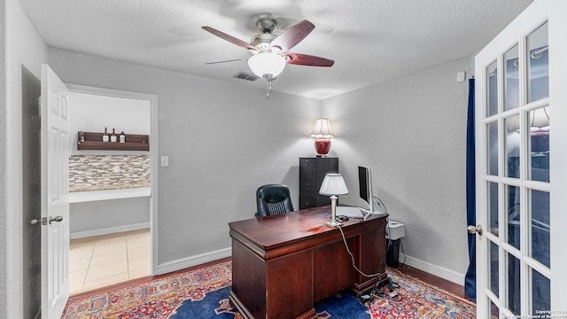 office featuring a textured ceiling, ceiling fan, and tile patterned floors