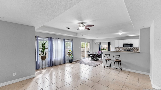 interior space featuring white cabinets, kitchen peninsula, a textured ceiling, backsplash, and a tray ceiling