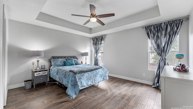 bedroom featuring dark wood-type flooring, ceiling fan, and a raised ceiling