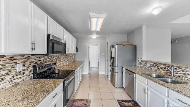 kitchen with decorative backsplash, white cabinetry, appliances with stainless steel finishes, and sink