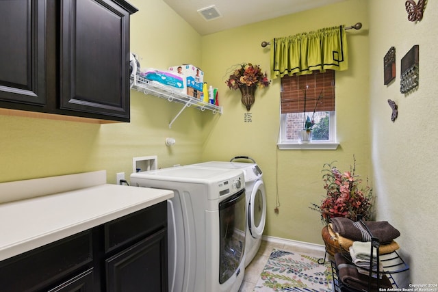 clothes washing area with cabinets, washing machine and clothes dryer, and light tile patterned floors