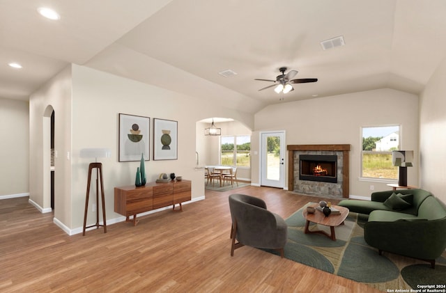 living room with a tiled fireplace, light hardwood / wood-style flooring, lofted ceiling, and ceiling fan