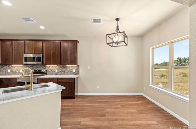 kitchen featuring plenty of natural light, light hardwood / wood-style flooring, hanging light fixtures, and stainless steel appliances