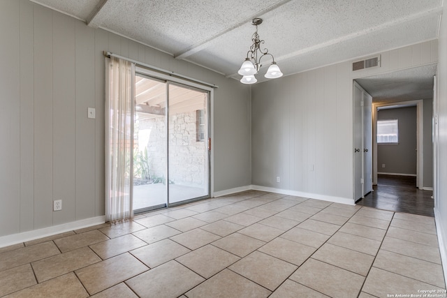 unfurnished room featuring wood walls, a textured ceiling, a notable chandelier, and light tile patterned floors