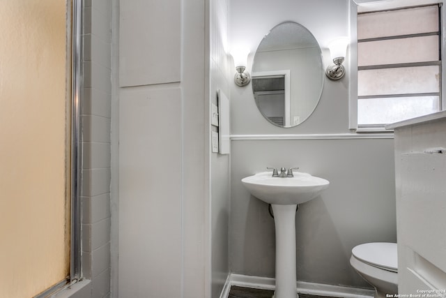 bathroom featuring walk in shower, toilet, and sink