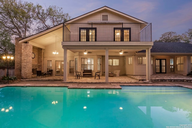 back house at dusk with a patio area, ceiling fan, and a balcony