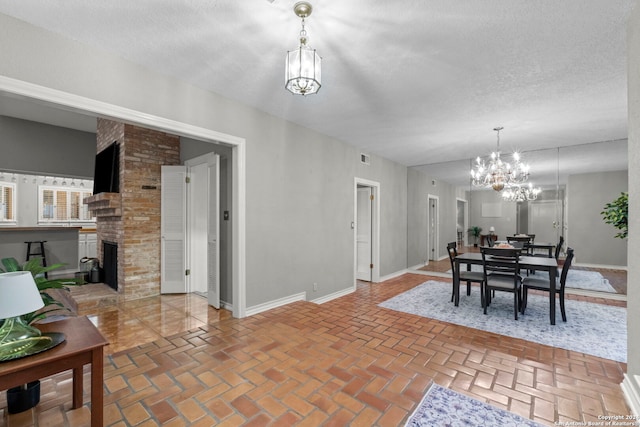 dining area featuring an inviting chandelier, a textured ceiling, and a fireplace