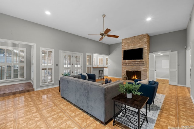 living room featuring a brick fireplace, ceiling fan, plenty of natural light, and light parquet floors