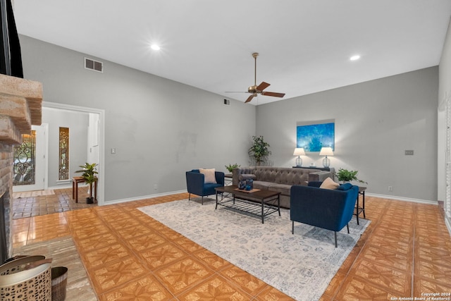 tiled living room with ceiling fan and a stone fireplace