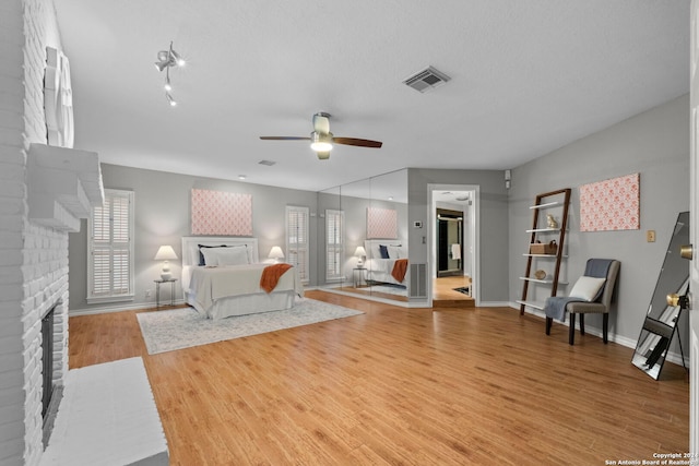 living room with ceiling fan, a textured ceiling, light hardwood / wood-style floors, and a fireplace