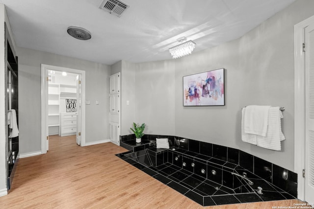 bathroom featuring a bath, hardwood / wood-style flooring, and a notable chandelier