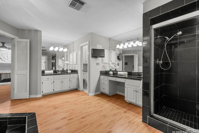 bathroom with hardwood / wood-style floors, vanity, toilet, and a shower with shower door