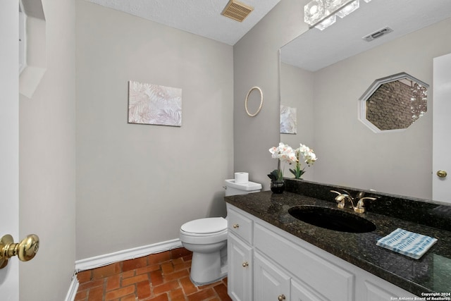 bathroom with toilet, vanity, and a textured ceiling