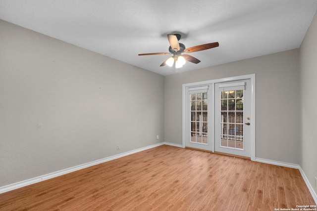 empty room with light hardwood / wood-style floors, ceiling fan, and french doors