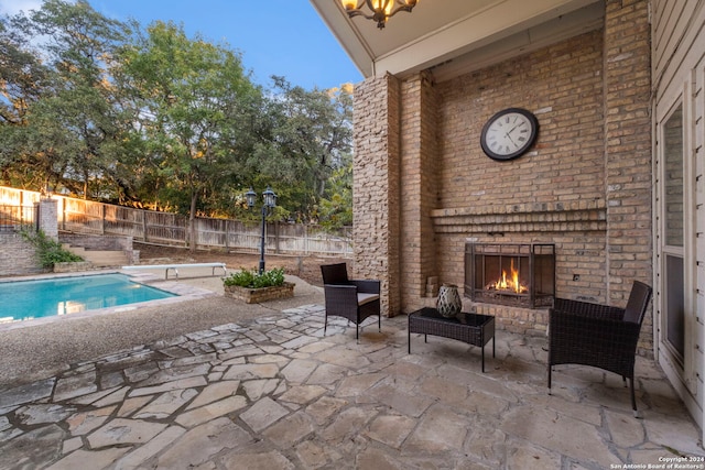 view of patio / terrace with a fenced in pool and an outdoor brick fireplace