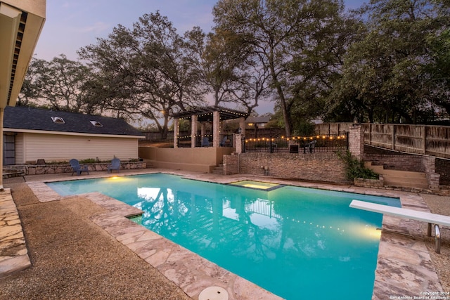 pool at dusk with a diving board and a patio area