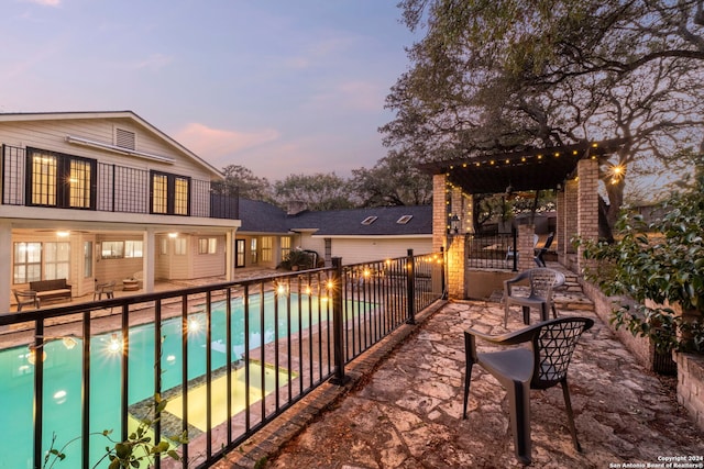 pool at dusk featuring a patio