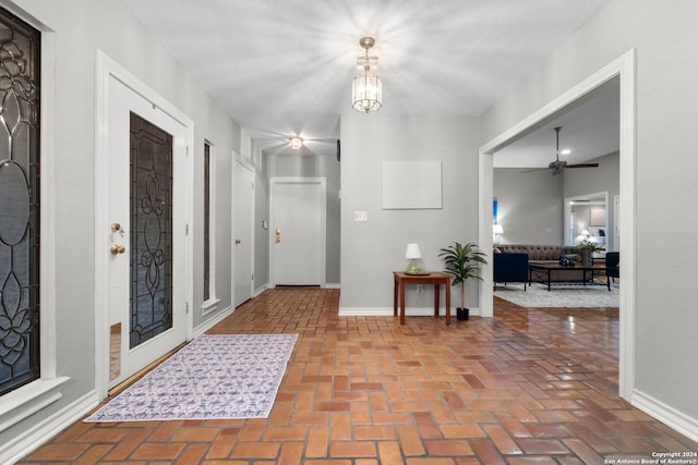 foyer featuring ceiling fan with notable chandelier