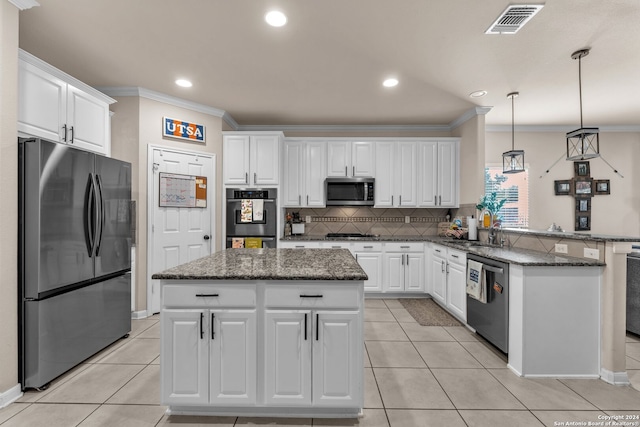 kitchen with white cabinets, appliances with stainless steel finishes, hanging light fixtures, and a kitchen island