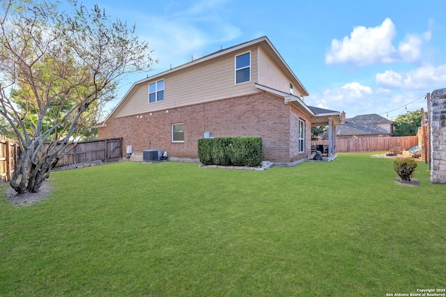 back of house featuring central AC unit and a yard