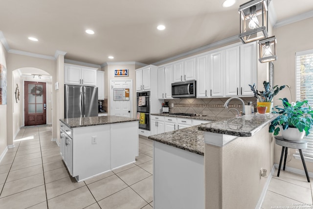 kitchen with stainless steel appliances, dark stone counters, white cabinetry, and a kitchen island