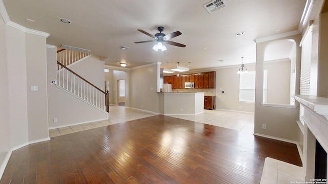 unfurnished living room with ornamental molding, ceiling fan with notable chandelier, and light hardwood / wood-style floors