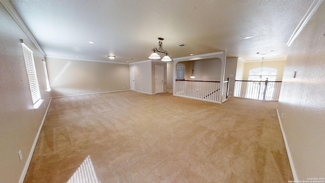 carpeted spare room featuring a textured ceiling, a wealth of natural light, a chandelier, and crown molding