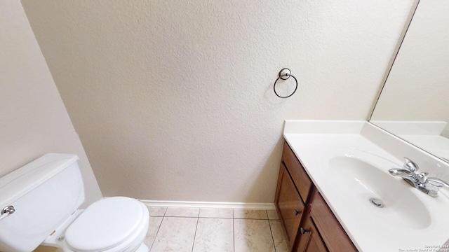 bathroom with toilet, vanity, and tile patterned floors