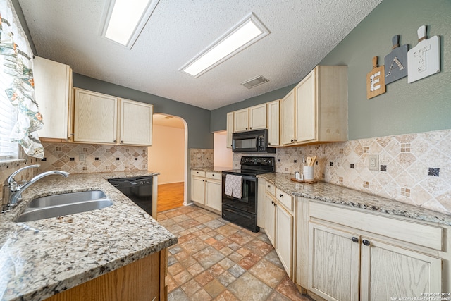 kitchen featuring light stone countertops, decorative backsplash, a textured ceiling, sink, and black appliances