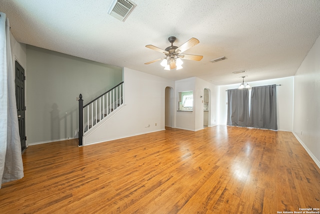 unfurnished living room with hardwood / wood-style flooring, ceiling fan with notable chandelier, and a textured ceiling