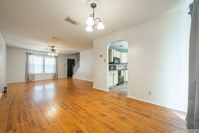 unfurnished living room featuring a textured ceiling, ceiling fan with notable chandelier, and light hardwood / wood-style floors