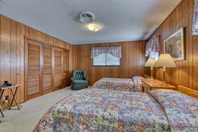 bedroom with a textured ceiling, carpet floors, wooden walls, and a closet